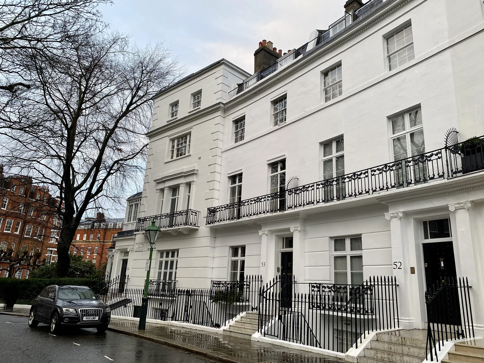 White stucco houses, black iron balconies and a garden-square tree on Egerton Crescent in South Kensington.